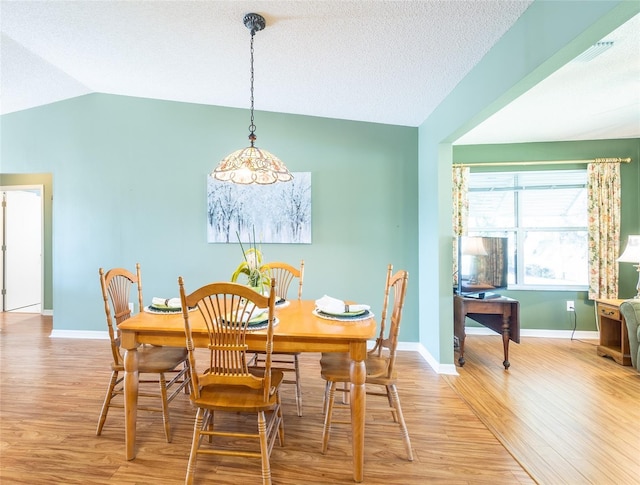 dining area with lofted ceiling, a textured ceiling, wood finished floors, and baseboards