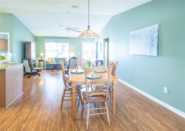 dining area with light wood-type flooring, vaulted ceiling, and baseboards