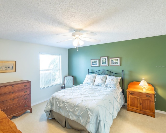 bedroom featuring light colored carpet, ceiling fan, a textured ceiling, and baseboards