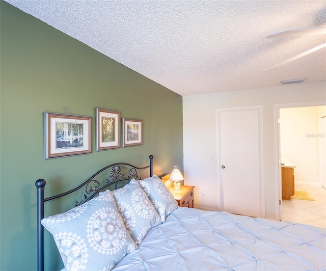 bedroom featuring vaulted ceiling, a textured ceiling, light tile patterned flooring, and visible vents