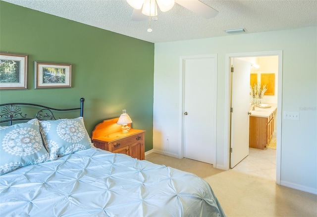 bedroom featuring visible vents, ensuite bathroom, light carpet, a textured ceiling, and baseboards