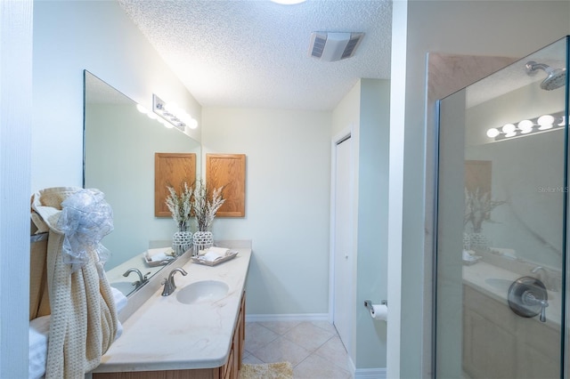 full bathroom featuring a textured ceiling, tile patterned flooring, vanity, visible vents, and a shower stall