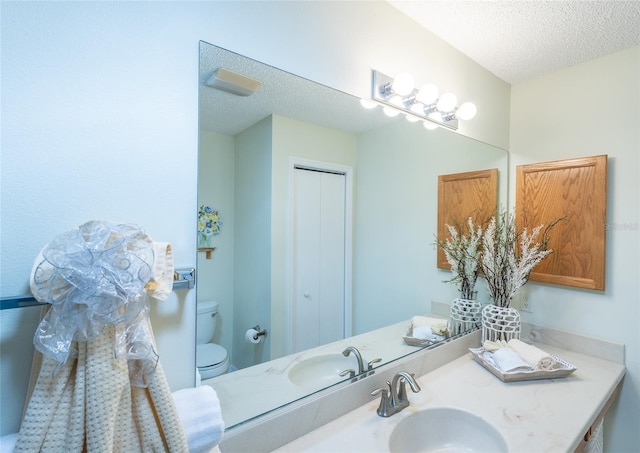 bathroom with a closet, a textured ceiling, toilet, and vanity