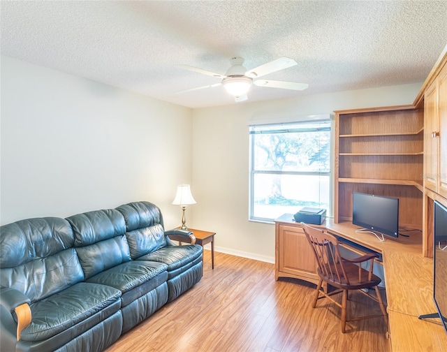 office space featuring a ceiling fan, light wood-type flooring, a textured ceiling, and baseboards