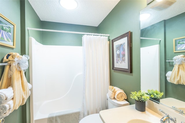 bathroom featuring visible vents, toilet, shower / bath combo with shower curtain, a textured ceiling, and vanity