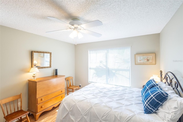 bedroom featuring a ceiling fan, a textured ceiling, and wood finished floors