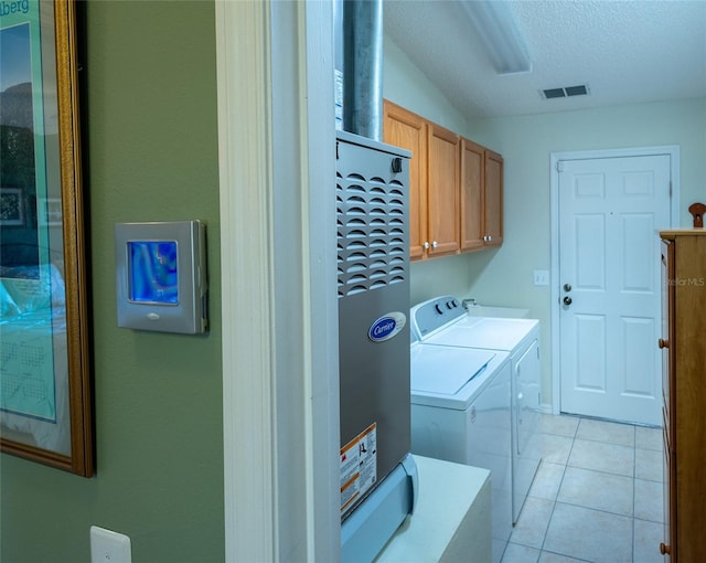 laundry room featuring light tile patterned floors, visible vents, cabinet space, a textured ceiling, and washer and dryer