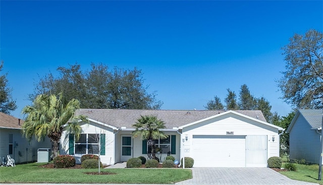 ranch-style home featuring a front lawn, decorative driveway, an attached garage, and cooling unit