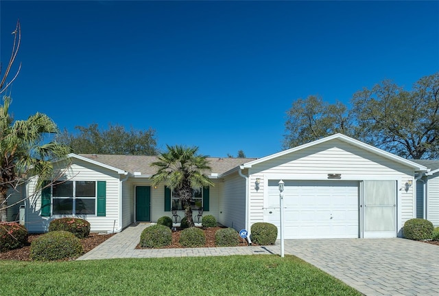 ranch-style home featuring a front yard, decorative driveway, and an attached garage