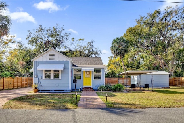 view of front facade featuring roof with shingles, fence, board and batten siding, and a front yard