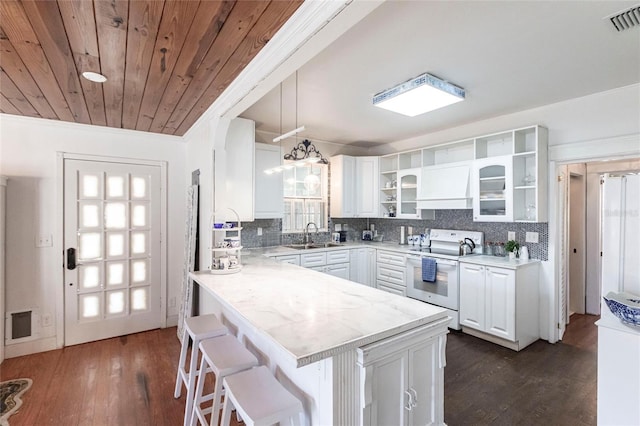 kitchen with pendant lighting, white range with electric stovetop, white cabinetry, a kitchen breakfast bar, and kitchen peninsula