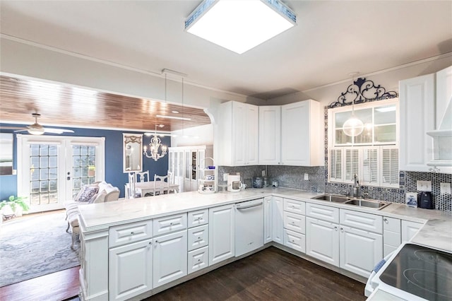 kitchen with sink, white cabinetry, hanging light fixtures, kitchen peninsula, and backsplash