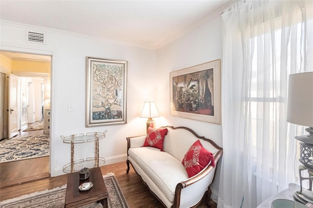 sitting room with ornamental molding and dark wood-type flooring