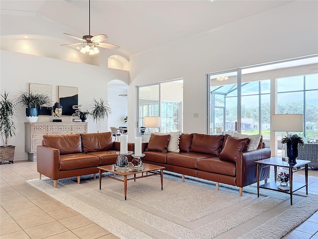 living room with a towering ceiling, light tile patterned floors, and ceiling fan