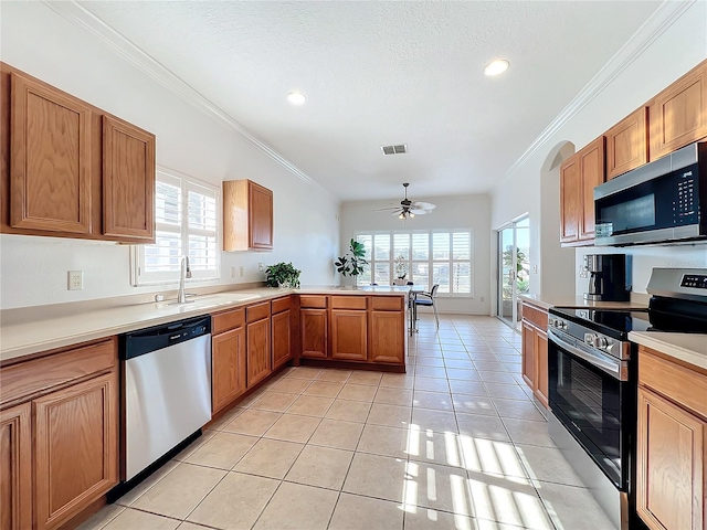 kitchen with stainless steel appliances, a wealth of natural light, sink, and light tile patterned floors