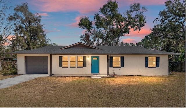 ranch-style house featuring a garage and a lawn