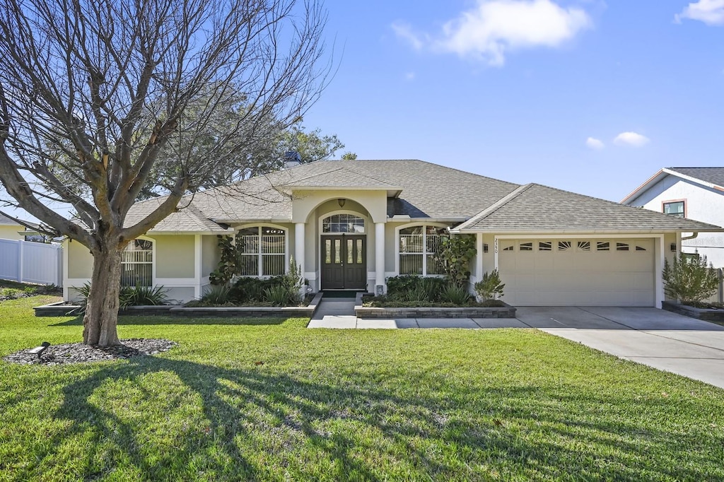 single story home with a garage and a front lawn