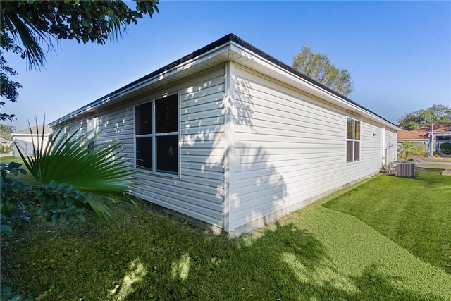 view of side of home featuring cooling unit and a yard