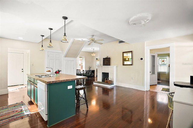 kitchen featuring sink, a breakfast bar area, a kitchen island with sink, hanging light fixtures, and green cabinetry