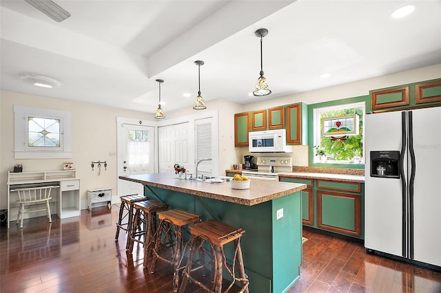 kitchen featuring hanging light fixtures, dark hardwood / wood-style floors, a kitchen breakfast bar, a kitchen island, and white appliances