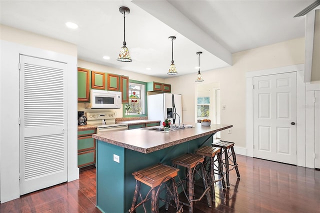 kitchen with dark hardwood / wood-style floors, a kitchen bar, hanging light fixtures, a center island with sink, and white appliances