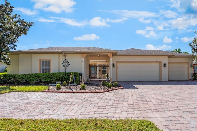 view of front of house featuring decorative driveway, an attached garage, and stucco siding