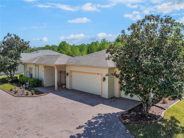 ranch-style house featuring a garage, decorative driveway, a shingled roof, and stucco siding