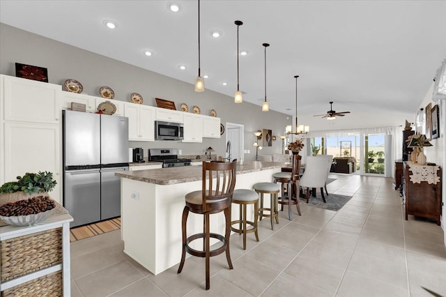 kitchen with pendant lighting, stainless steel appliances, a breakfast bar, and a kitchen island with sink