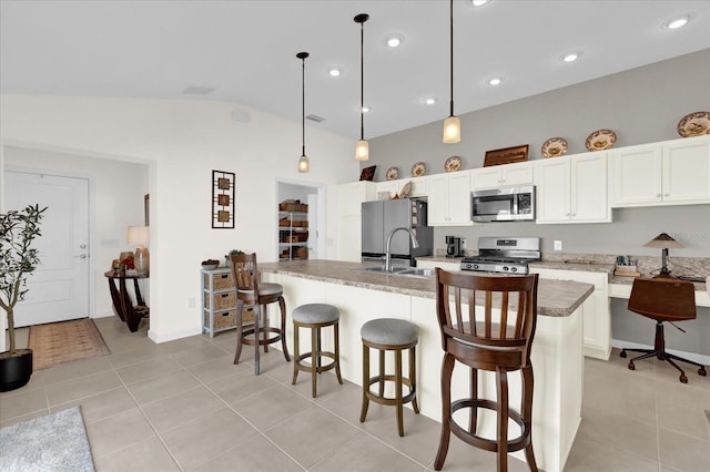 kitchen featuring stone countertops, hanging light fixtures, light tile patterned floors, stainless steel appliances, and a kitchen island with sink