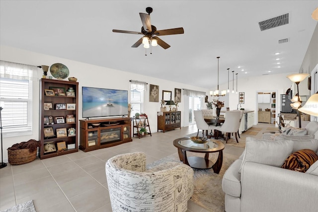 living room featuring ceiling fan with notable chandelier and light tile patterned floors