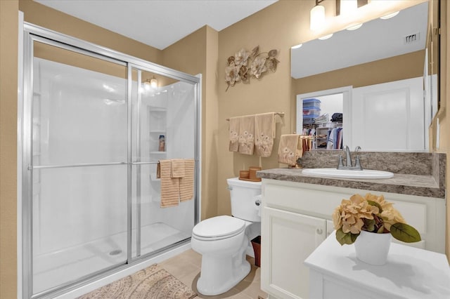 bathroom featuring vanity, toilet, a shower with shower door, and tile patterned flooring