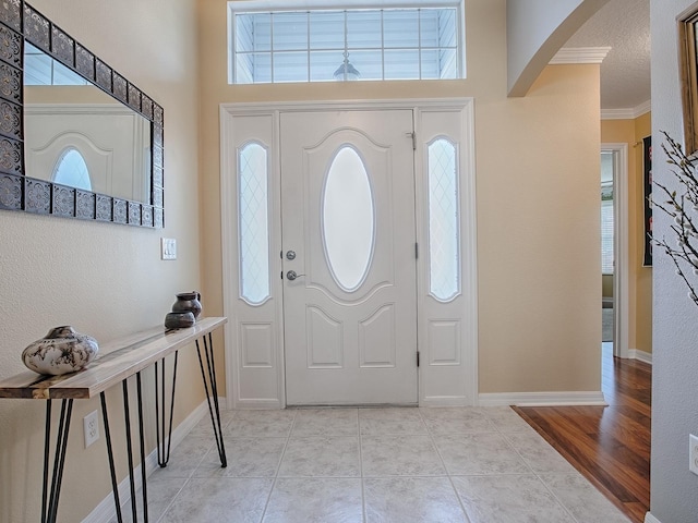 foyer entrance featuring ornamental molding, a textured ceiling, and light tile patterned floors