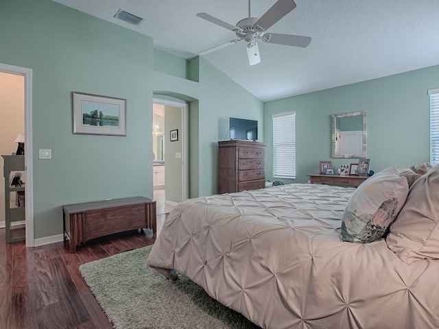 bedroom featuring lofted ceiling, ensuite bath, ceiling fan, dark hardwood / wood-style floors, and a textured ceiling