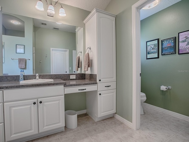 bathroom featuring tile patterned flooring, vanity, a notable chandelier, and toilet