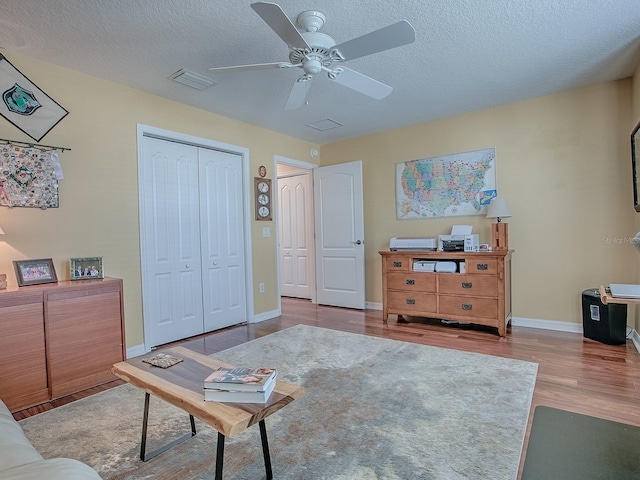 sitting room featuring ceiling fan, light hardwood / wood-style flooring, and a textured ceiling