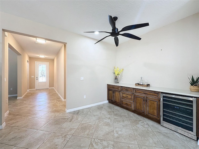 interior space with a textured ceiling, beverage cooler, and light tile patterned floors