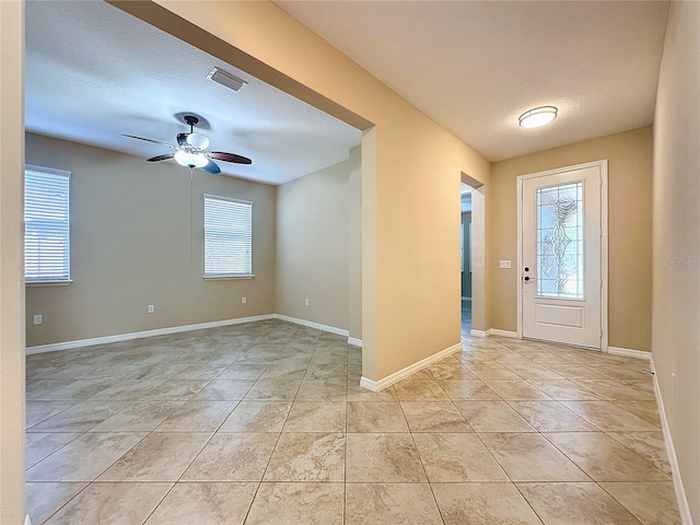 foyer with light tile patterned floors, ceiling fan, and a textured ceiling