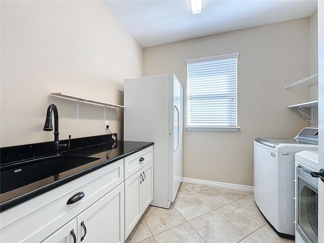 laundry room featuring light tile patterned flooring, sink, washer and clothes dryer, and cabinets