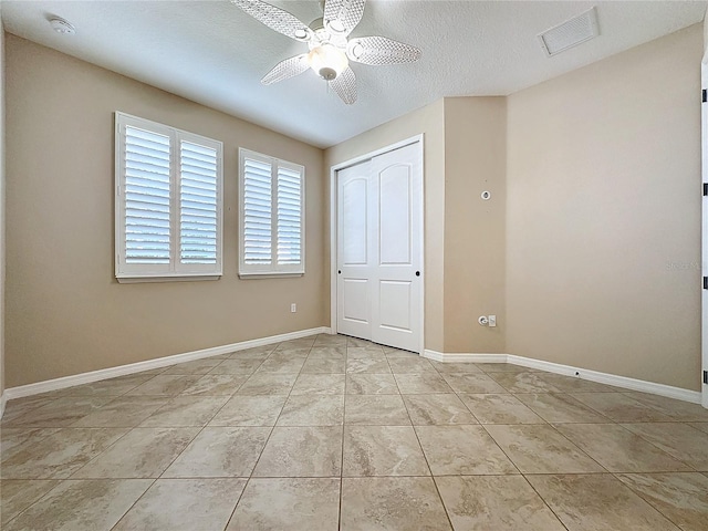 unfurnished bedroom featuring a textured ceiling, a closet, light tile patterned flooring, and ceiling fan