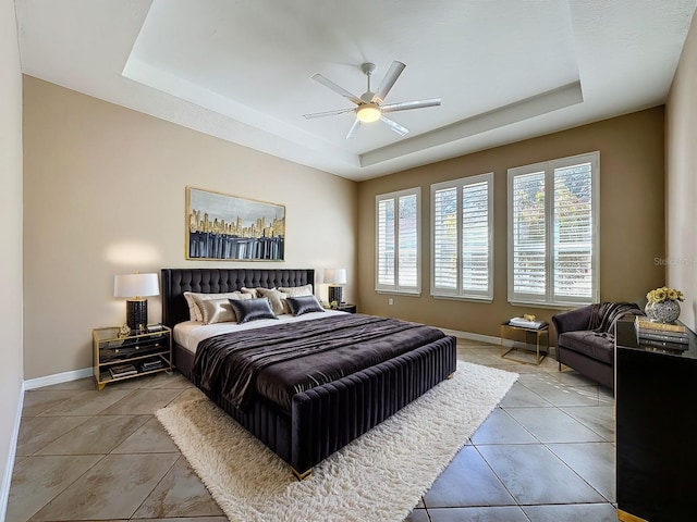 tiled bedroom with ceiling fan and a raised ceiling