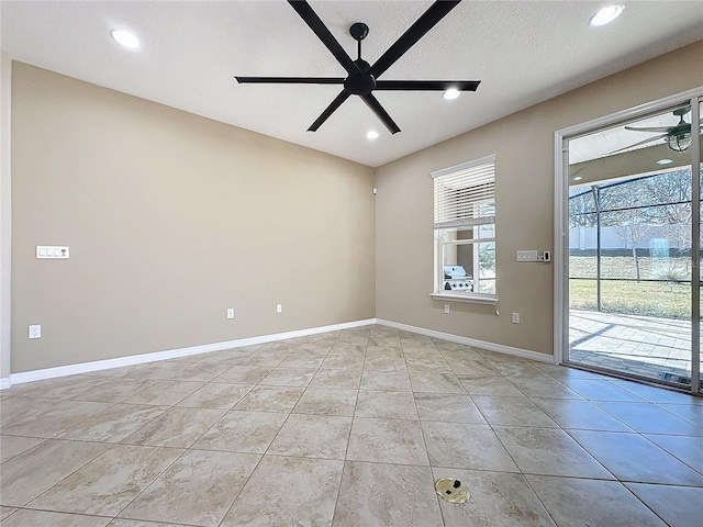 tiled empty room with ceiling fan and a textured ceiling