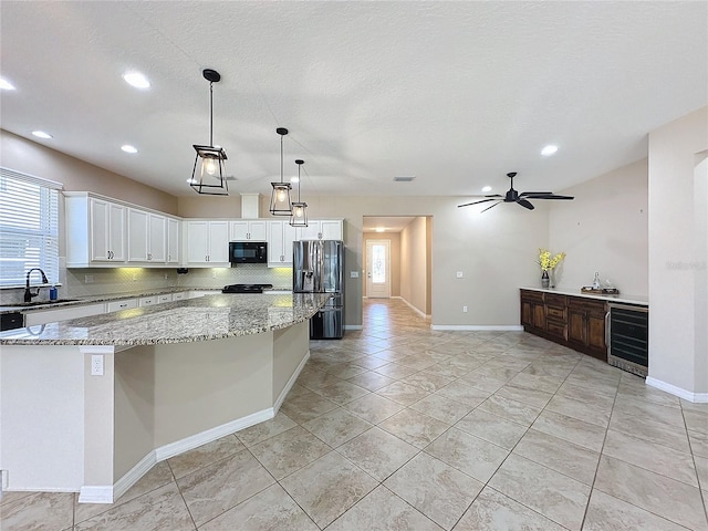 kitchen featuring decorative light fixtures, black appliances, sink, white cabinets, and beverage cooler