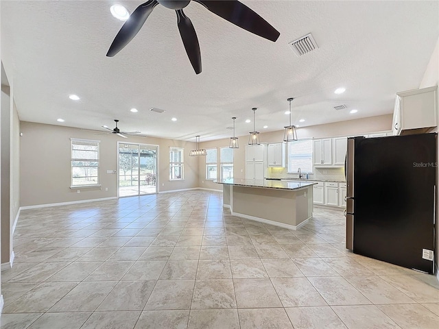 kitchen featuring light tile patterned flooring, a center island, white cabinetry, pendant lighting, and stainless steel fridge