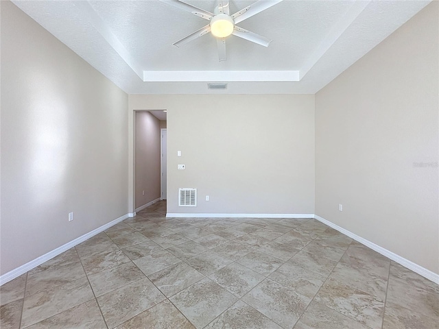 spare room featuring ceiling fan, a raised ceiling, and a textured ceiling