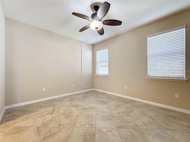 tiled empty room featuring ceiling fan and a textured ceiling