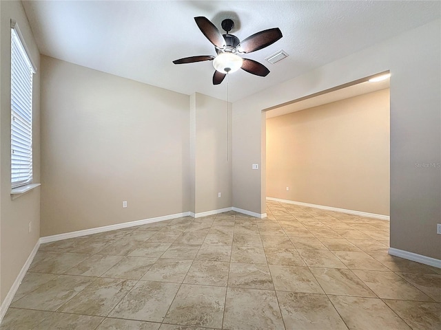 tiled spare room with ceiling fan