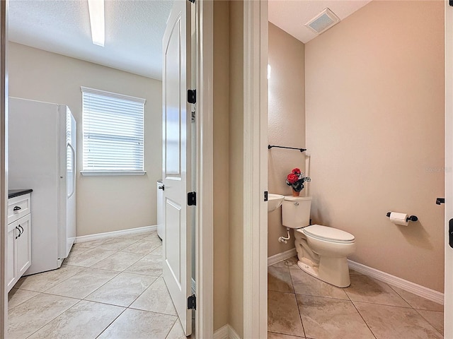 bathroom featuring vanity, a textured ceiling, washer / dryer, toilet, and tile patterned floors