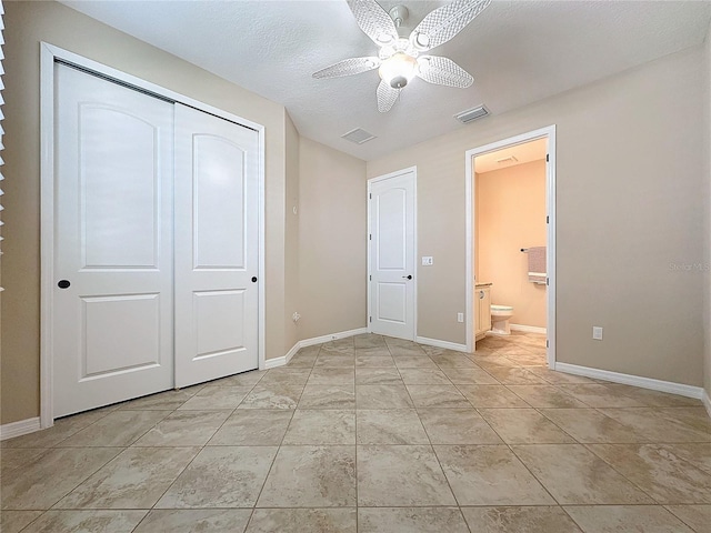 unfurnished bedroom featuring a closet, light tile patterned floors, a textured ceiling, ensuite bathroom, and ceiling fan