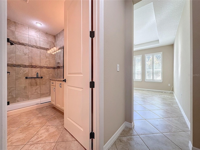 bathroom with tiled shower, a textured ceiling, and tile patterned floors