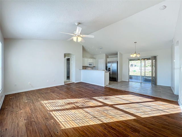 unfurnished living room with ceiling fan, lofted ceiling, light hardwood / wood-style floors, and a textured ceiling